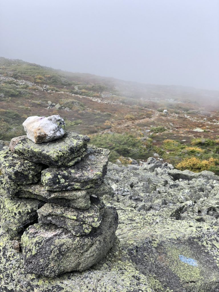A misty ridge and cairn seen while hiking Mt Adams in the White Mountains, New Hampshire