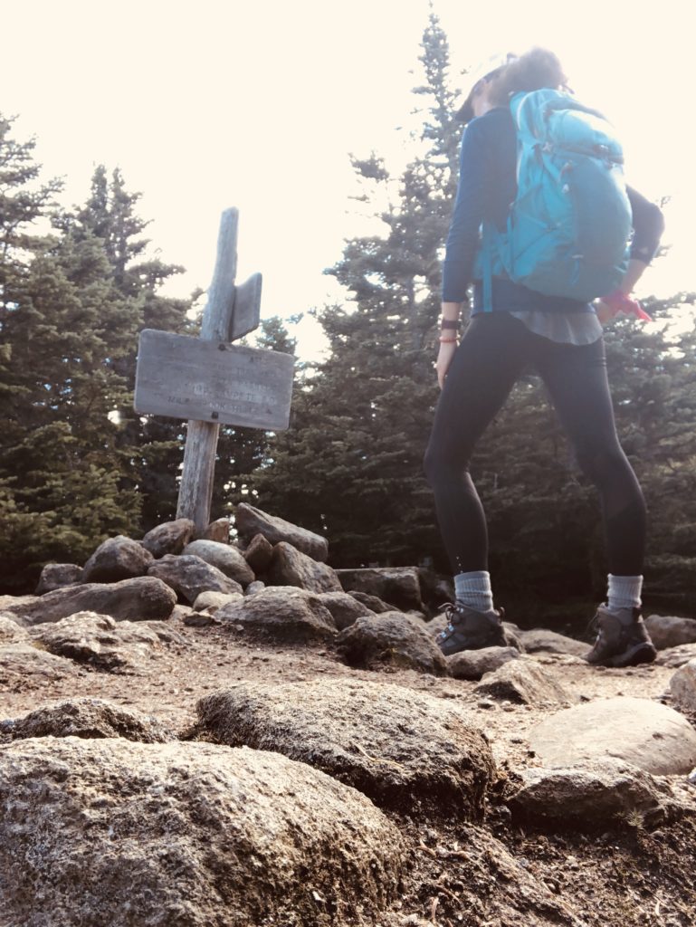 A person looking at a trail sign while hiking the Carter range in the White Mountains, New Hampshire