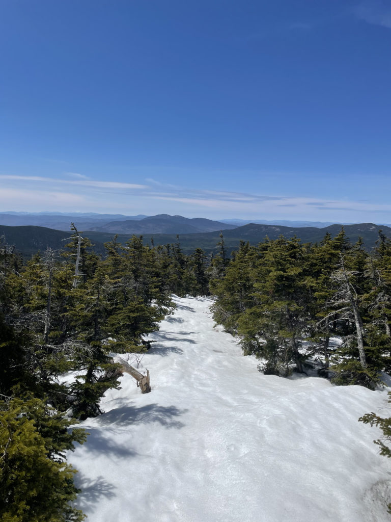 A snowy trail and the distant mountains, seen while hiking Sugarloaf and Spaulding Mountains in Western Maine