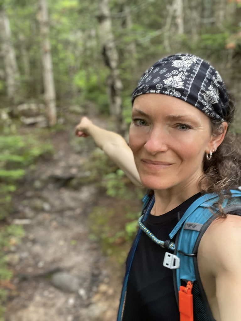 Hiker pointing to the trail, seen while hiking Mt. Isolation in the White Mountain National Forest, New Hampshire