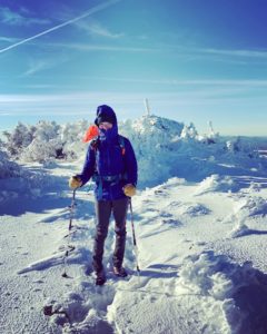 Guide Sarah Holman at the summit of Mount Bigelow in Maine during the winter.